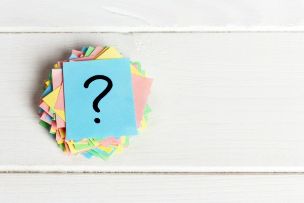question mark on a stack of colored papers depicting FAQs about Ductless HVAC vs. Window AC Systems