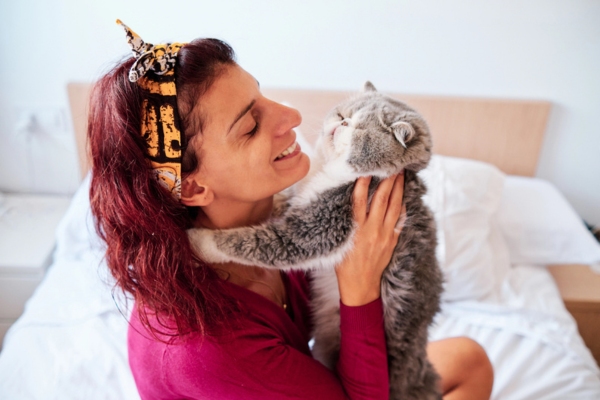 woman hugging her cat in the bedroom depicting cozy indoor warmth during winter