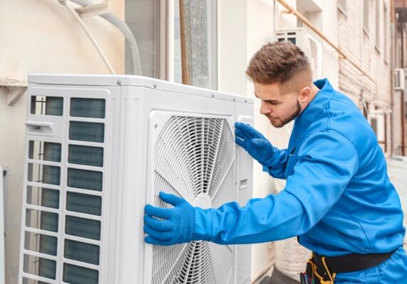 HVAC technicians installing ductless air conditioner outdoor unit